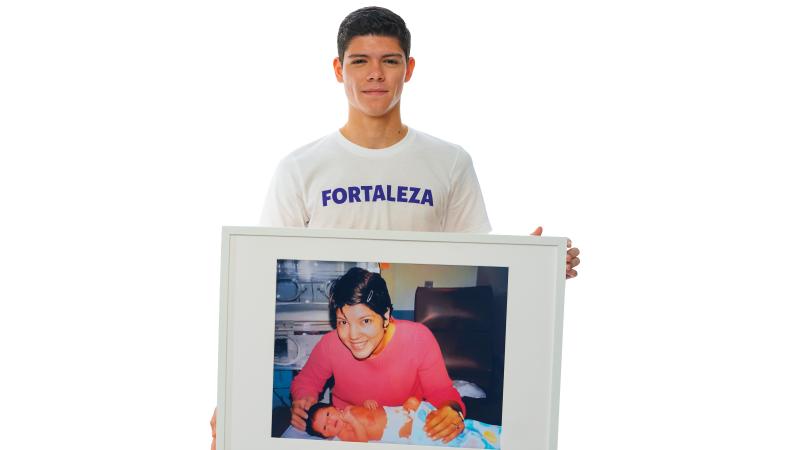 Ismael holding an image of mom and him as a premie